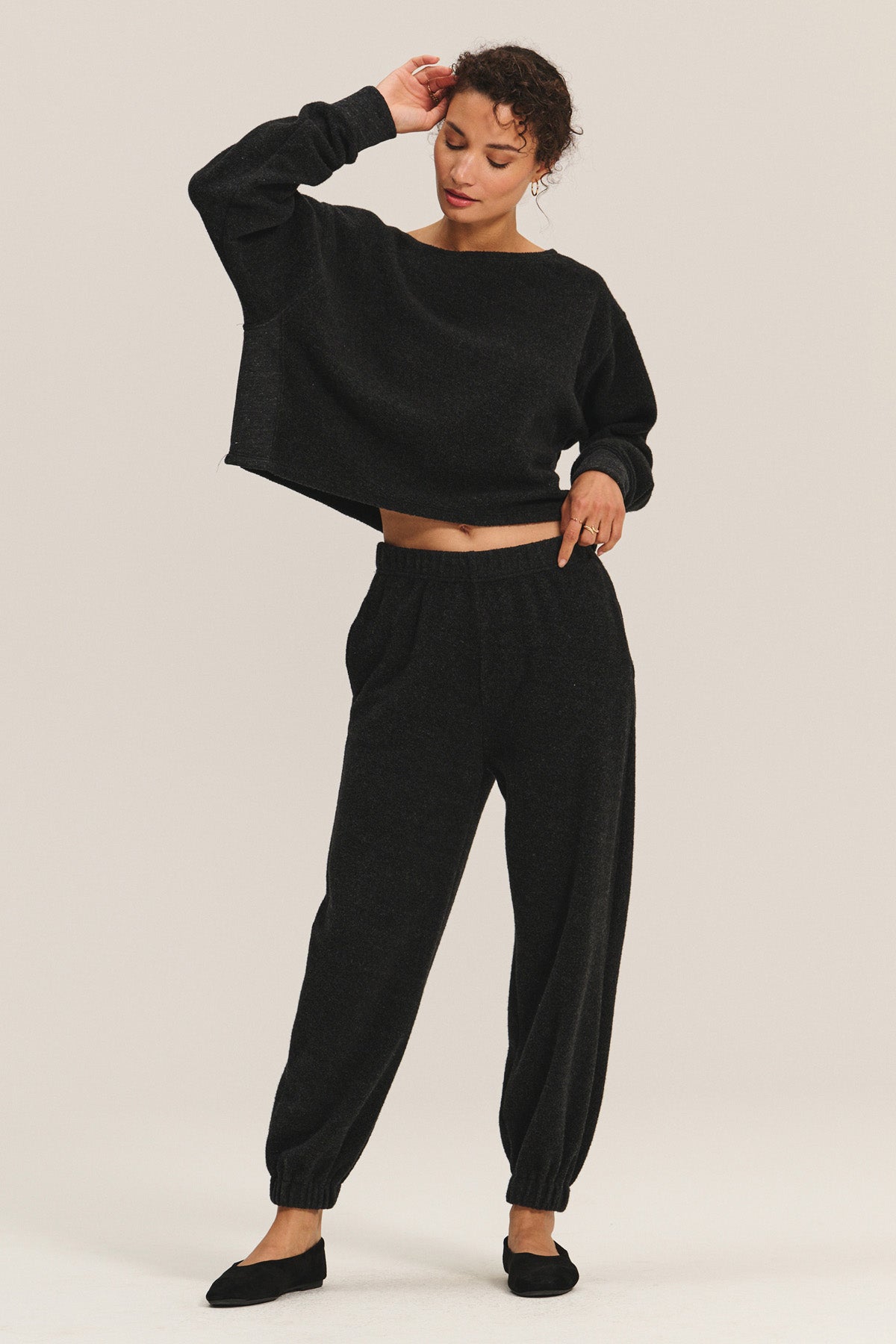 Someone wearing the DAWN JOGGER by Velvet by Graham & Spencer, styled with a loose black long-sleeve top, stands with one hand on their head and the other on their hip.