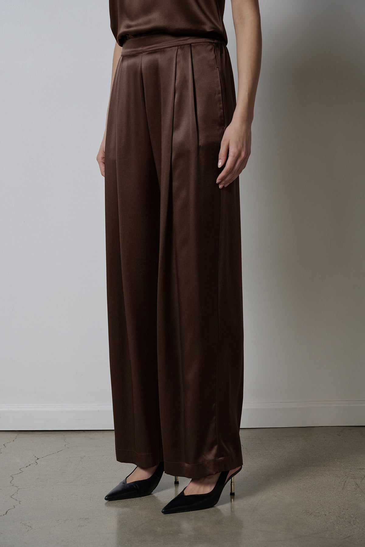   The model is wearing a brown silk jumpsuit with wider leg pants in Velvet by Jenny Graham's MANHATTAN PANT. 