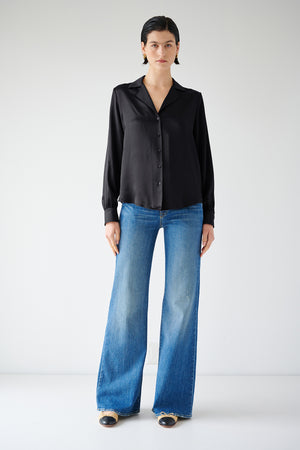 The model is wearing a timeless SOHO TOP blouse by Velvet by Jenny Graham and blue wide leg jeans.