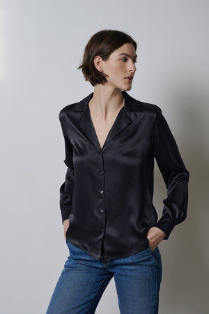 The model is wearing a timeless SOHO TOP blouse from Velvet by Jenny Graham with button-up detailing, paired with jeans.