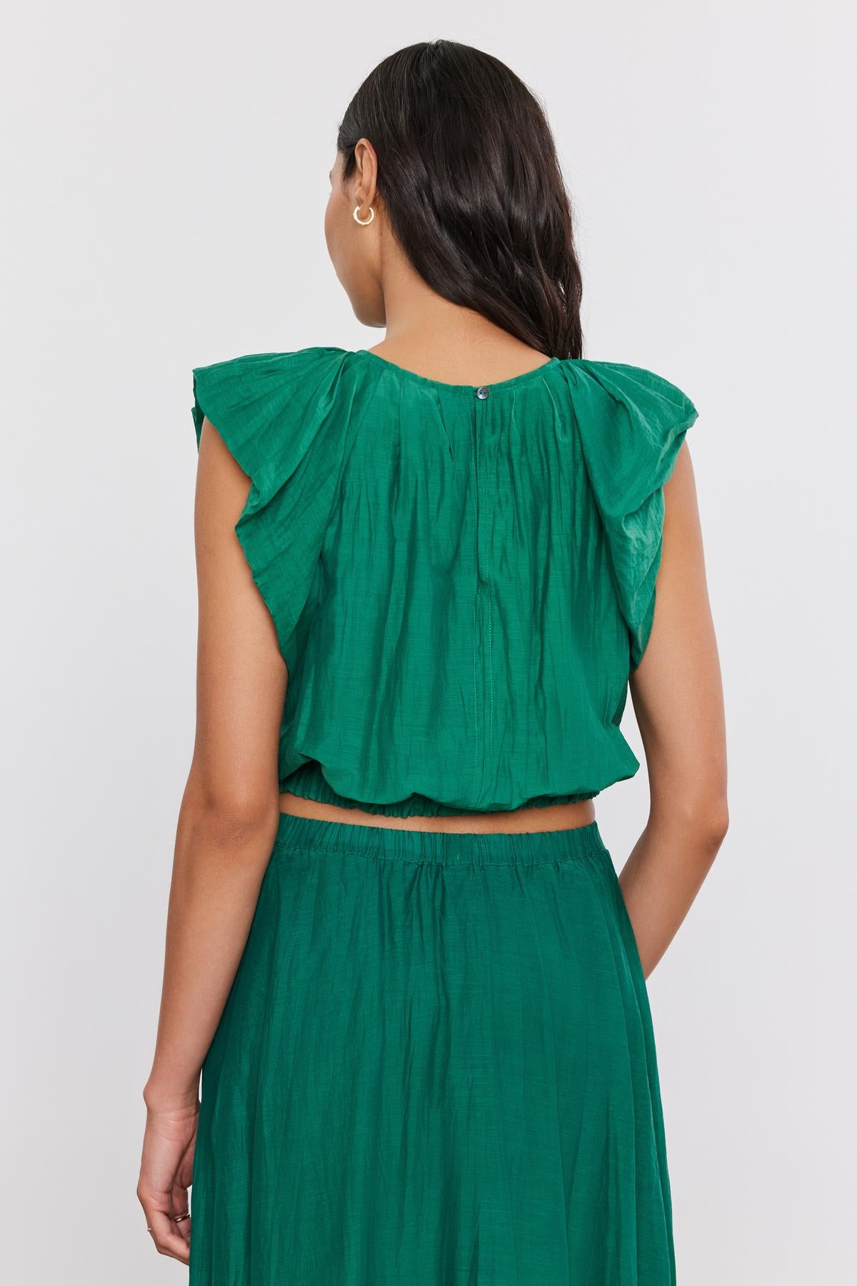   A woman viewed from behind wearing a Velvet by Graham & Spencer AMORA TOP with a crew neckline and matching skirt, standing against a plain white background. 