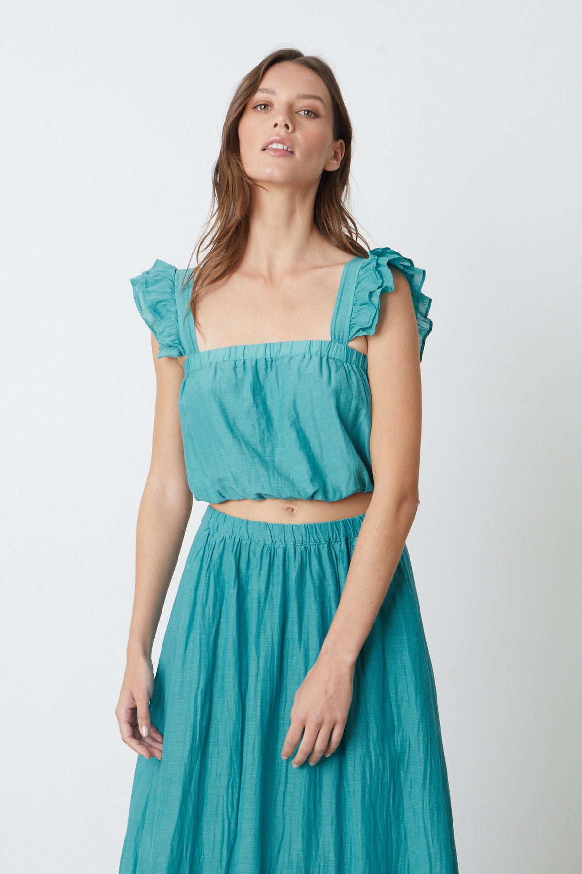   The model is wearing a CROPPED TANK TOP by Velvet by Graham & Spencer with ruffled sleeves. 