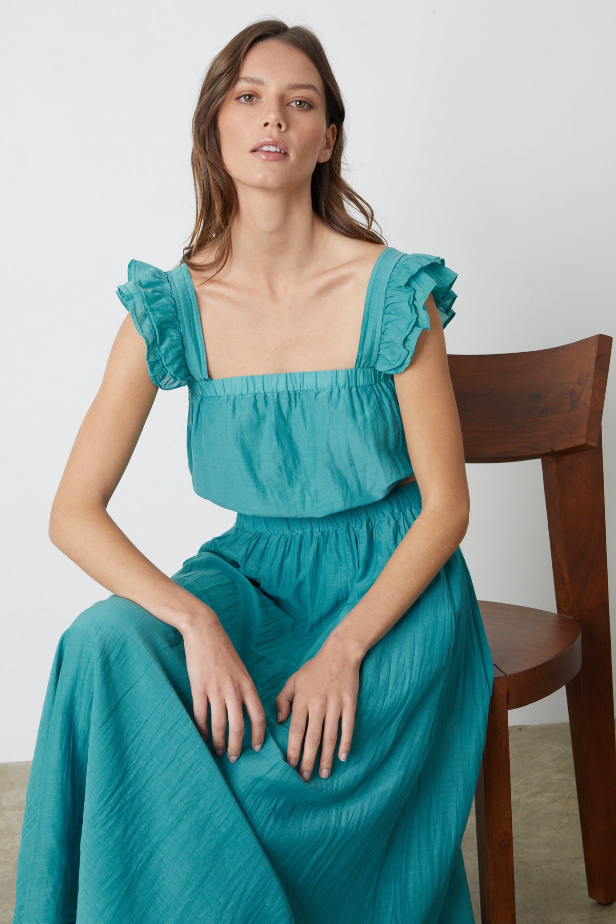   The model is wearing a teal Velvet by Graham & Spencer ruffled maxi dress. 