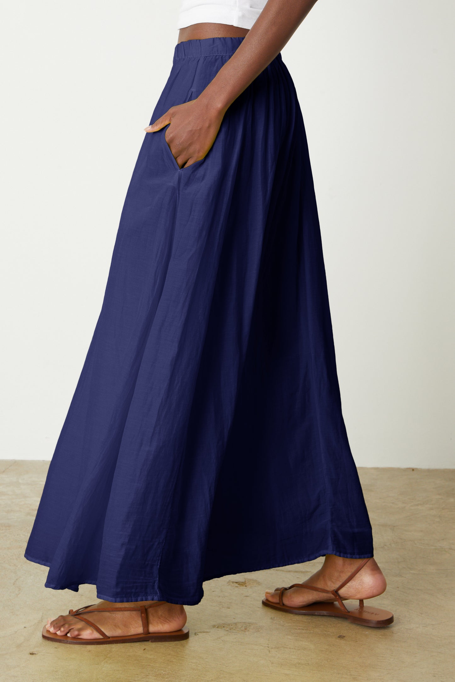 Side view of Mariela Maxi Skirt in cavern blue by Velvet by Graham & Spencer and white sandals.-26577336893633
