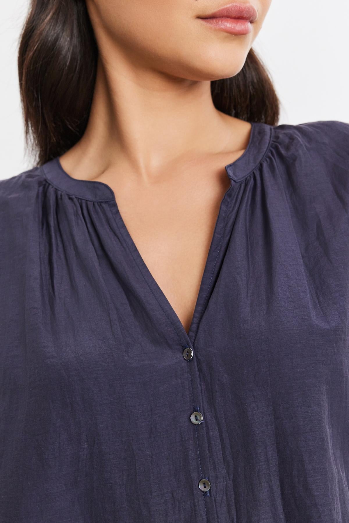   Close-up of a person wearing the MEL SILK COTTON VOILE BUTTON-UP TOP by Velvet by Graham & Spencer, featuring gathered detailing near the neckline, with long dark hair. Only the lower part of the face and upper torso are visible. 