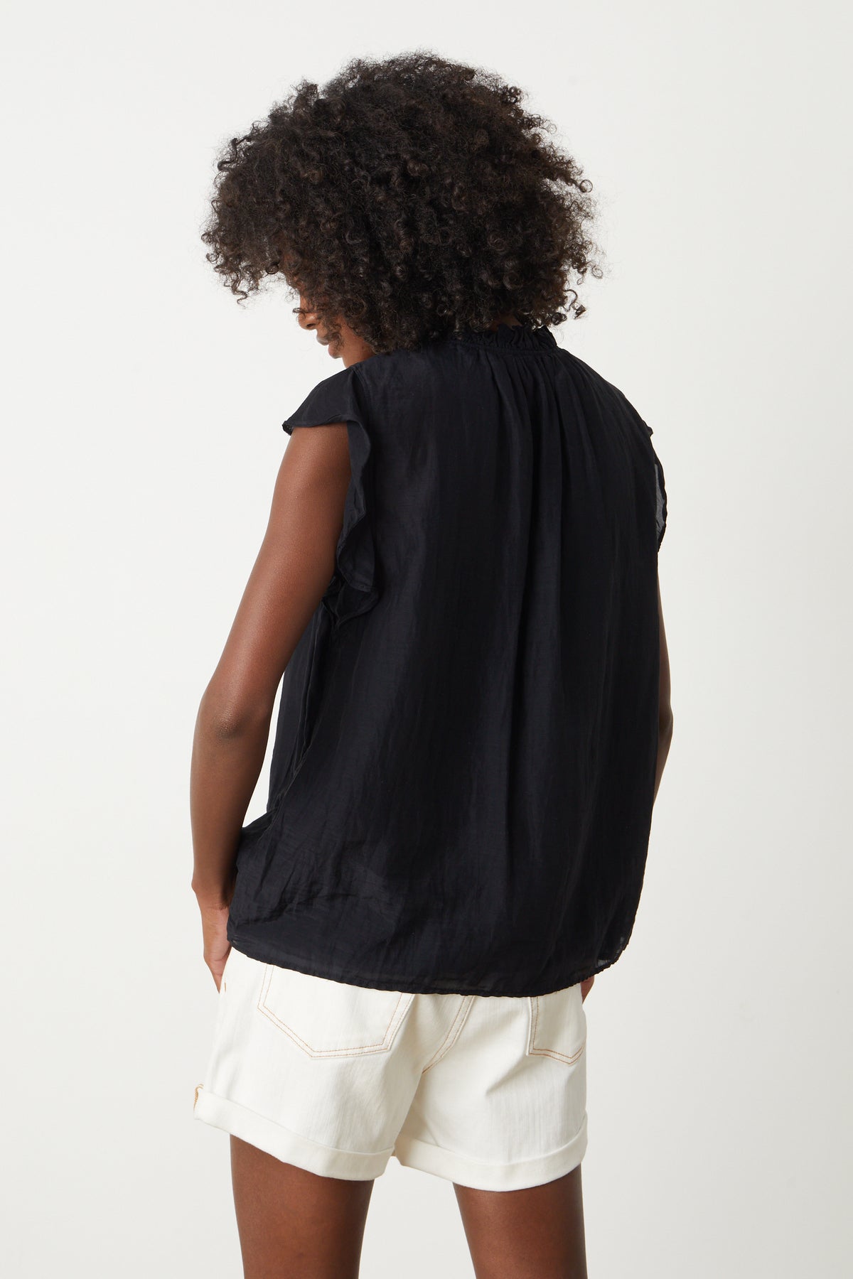   The back view of a woman wearing a Velvet by Graham & Spencer Melanie V-Neck Blouse and shorts. 