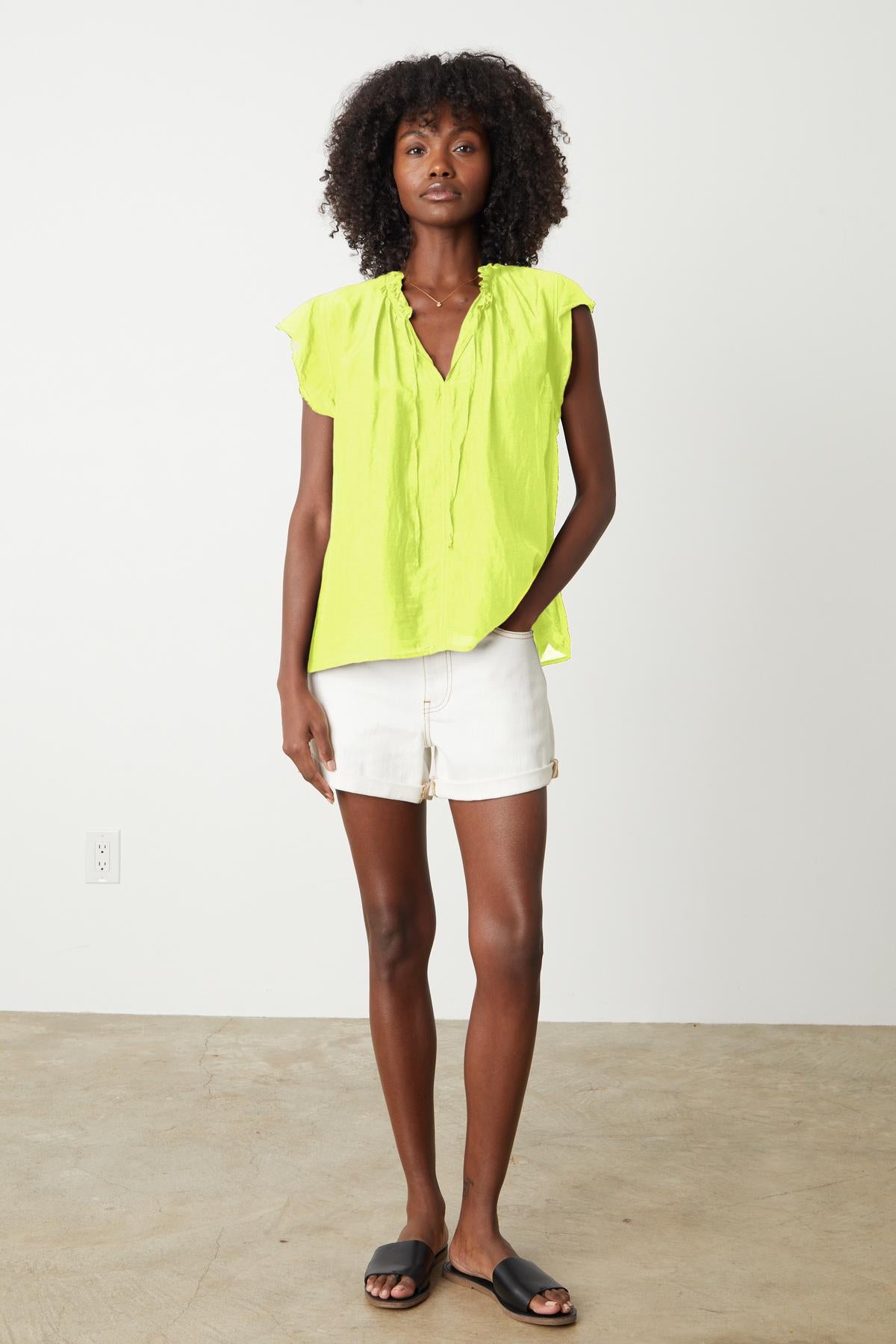   the model is wearing a Velvet by Graham & Spencer MELANIE V-NECK BLOUSE and white shorts. 