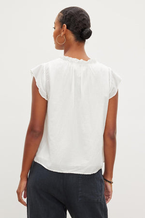 The back view of a woman wearing a Velvet by Graham & Spencer Melanie V-Neck Blouse with ruffled sleeves.