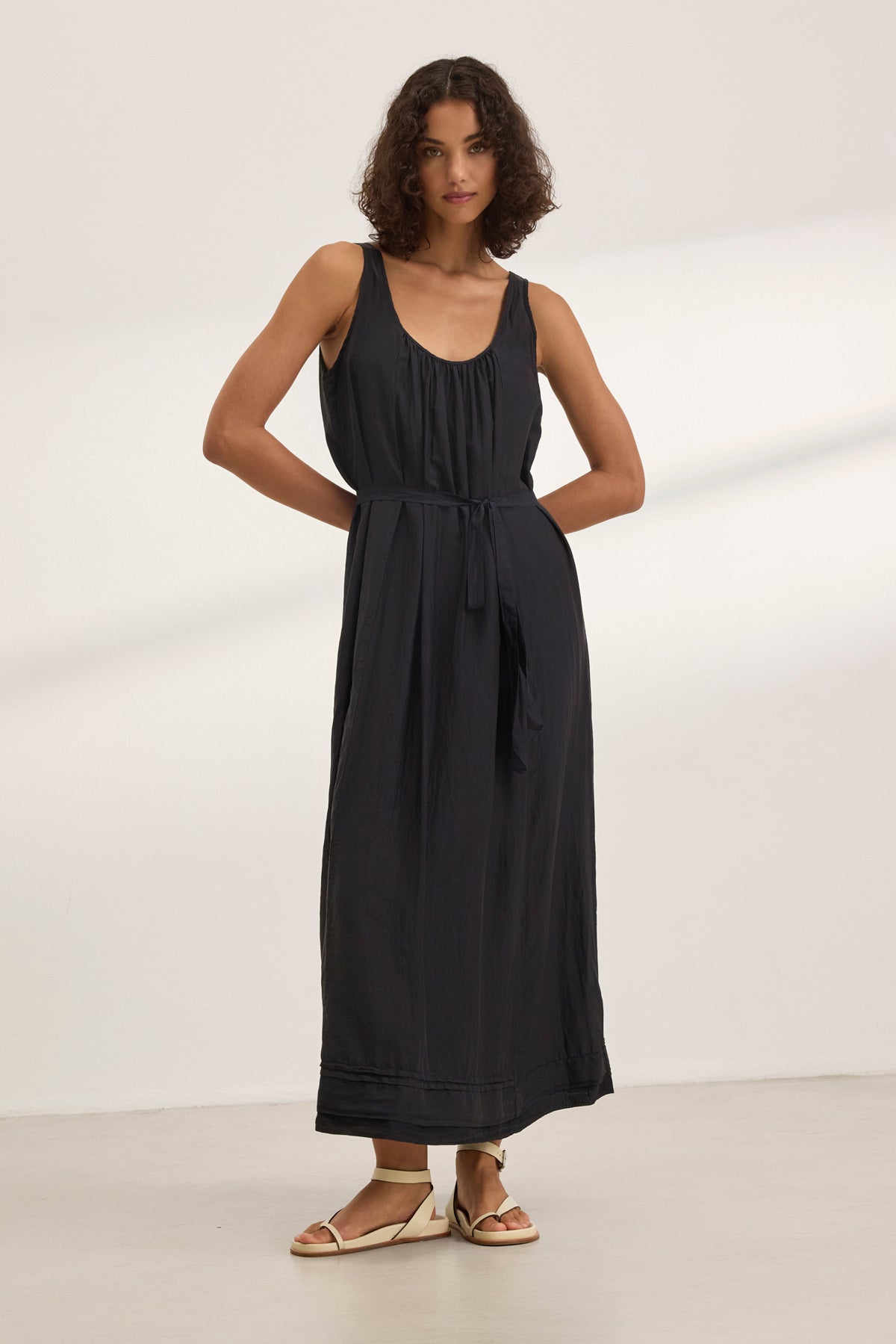 A person models the BAYOU SILK COTTON VOILE DRESS by Velvet by Graham & Spencer, a sleeveless black maxi paired with sandals, set against a white backdrop for versatile styling.-38801130619073