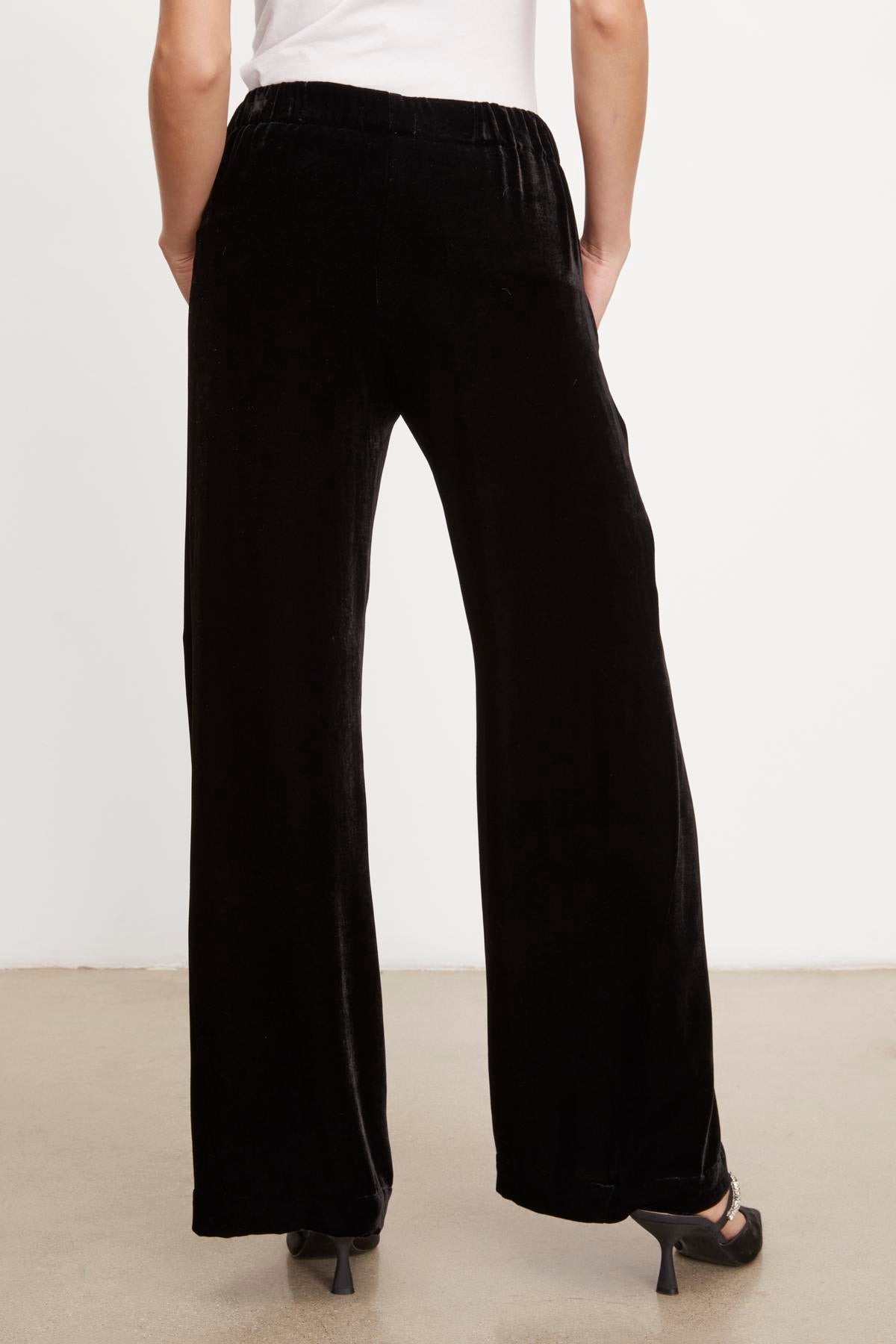   The back view of a woman wearing FRIDA silk velvet wide leg pants by Velvet by Graham & Spencer. 