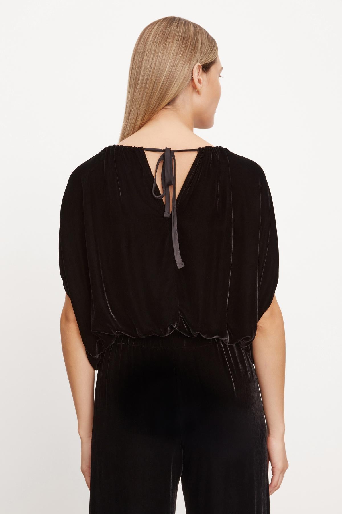   The back view of a woman wearing a NOA SILK VELVET CROPPED TOP with an adjustable tie by Velvet by Graham & Spencer. 