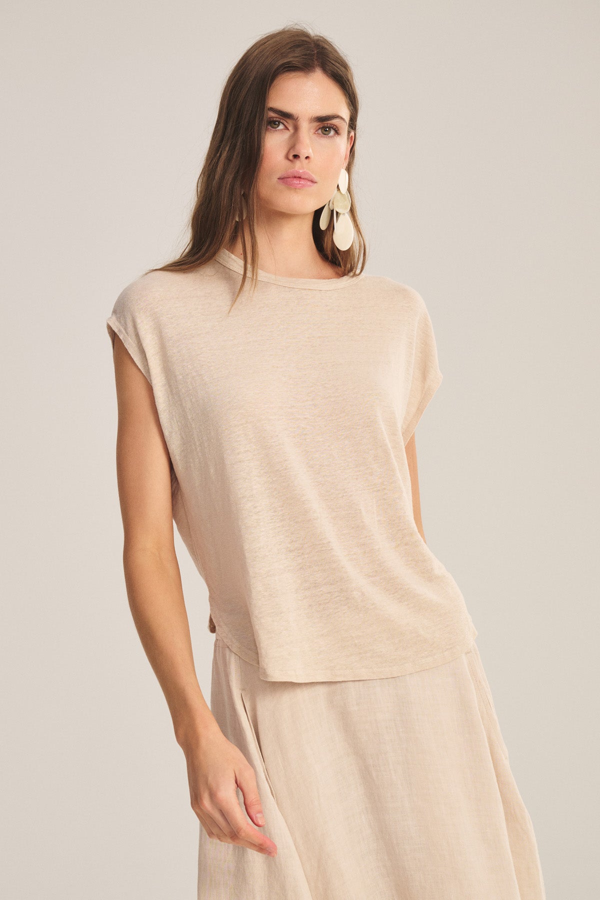 Woman wears the SINCLAIR TEE by Velvet by Graham & Spencer, a matching linen knit sleeveless top and beige cocoon silhouette skirt, standing against a plain background and looking at the camera.-41008412033217