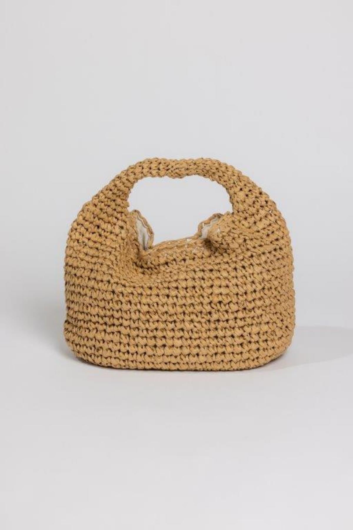   A small, hand-woven paper straw Slouch Bag by Velvet by Graham & Spencer with a rounded shape and integrated handle, displayed against a plain, light background. 