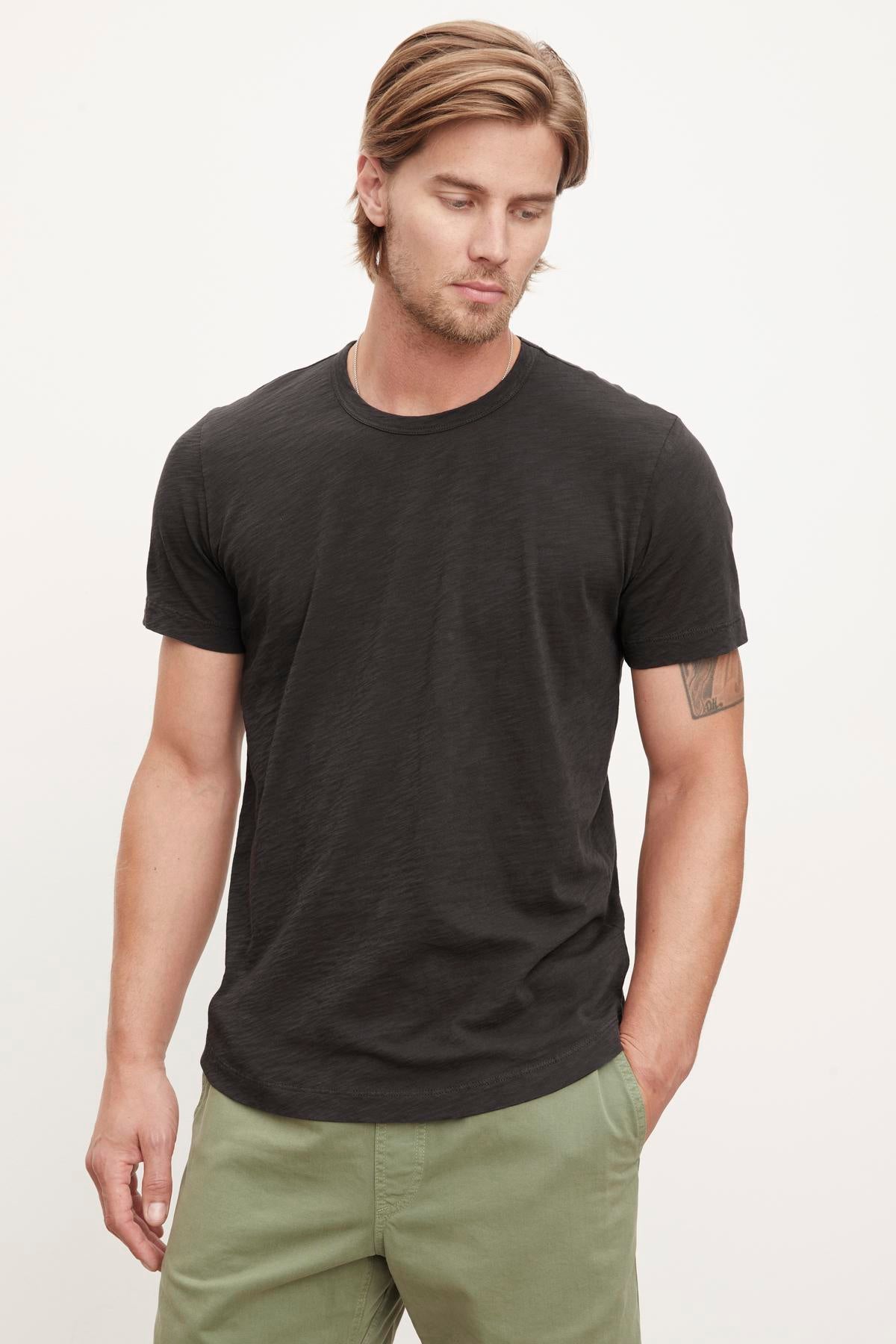   Man wearing a Velvet by Graham & Spencer heathered texture, dark grey AMARO TEE crew neck t-shirt and green pants. 