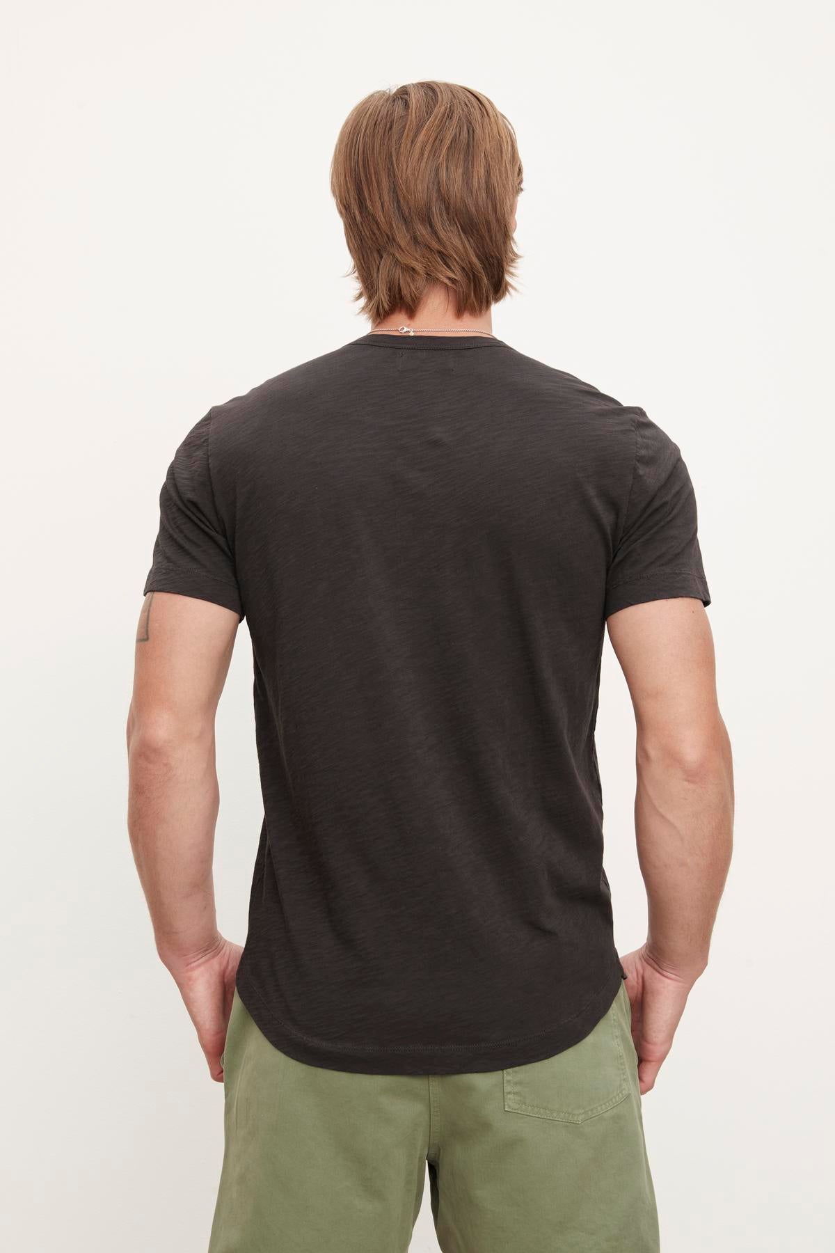 Man standing with his back to the camera wearing a dark, slub knit AMARO TEE by Velvet by Graham & Spencer and green pants.-36299660165313
