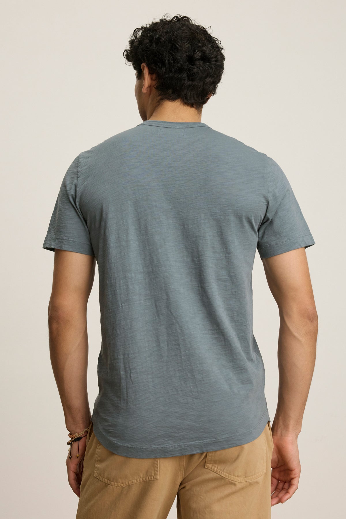 Someone wearing the AMARO TEE by Velvet by Graham & Spencer, a lightweight cotton crew neck, paired with tan pants, stands with their back to the camera against a plain background.-39446016131265
