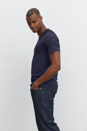 A man wearing a navy AMARO crew neck slub tee by Velvet by Graham & Spencer and jeans.