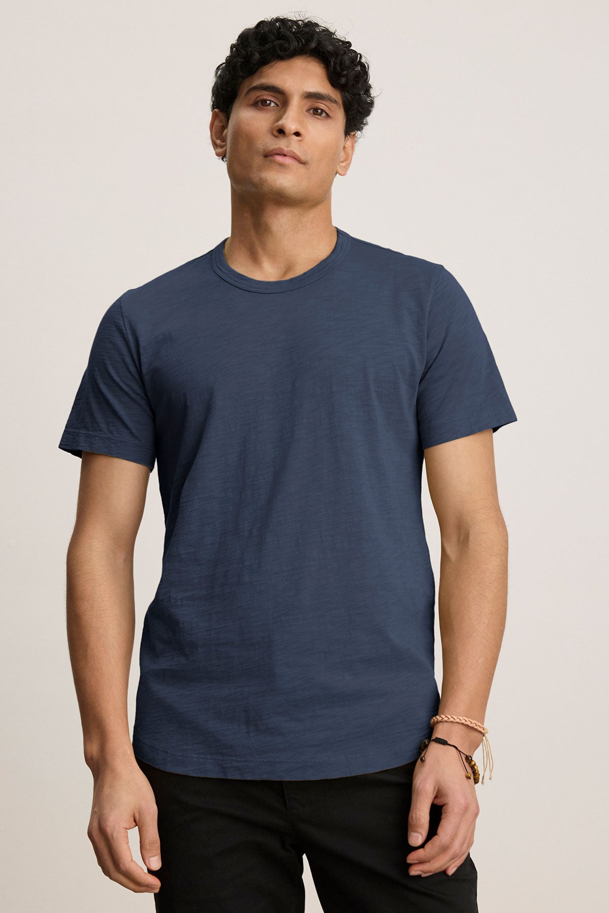   Person wearing a navy blue AMARO TEE by Velvet by Graham & Spencer and black pants, standing against a plain background. 