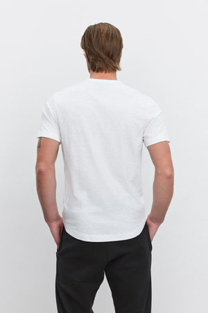 The back of a man wearing a Velvet by Graham & Spencer AMARO CREW NECK SLUB TEE with a curved hemline and black pants.