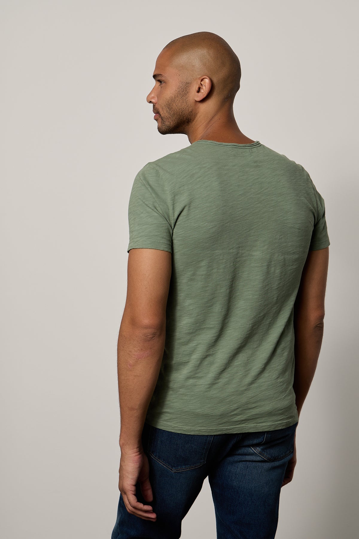   the back of a man wearing jeans and a green CHAD RAW EDGE COTTON SLUB POCKET TEE by Velvet by Graham & Spencer. 