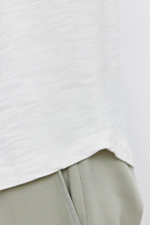 Close-up of a Velvet by Graham & Spencer SPADER TEE partially covering light gray pants with an elastic waistband.