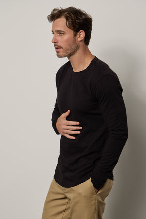 A man wearing a Velvet by Graham & Spencer KAI CREW NECK TEE khaki pants with a subtle curve.