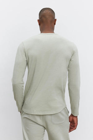 A person is seen from behind wearing a long-sleeve, light gray KAI TEE by Velvet by Graham & Spencer with a classic crew neckline and matching pants against a plain white background.