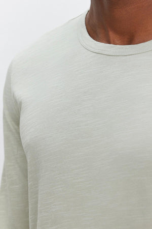 Close-up of a person wearing a light grey, textured cotton slub long-sleeve shirt with a classic crew neckline (KAI TEE by Velvet by Graham & Spencer) against a plain background.