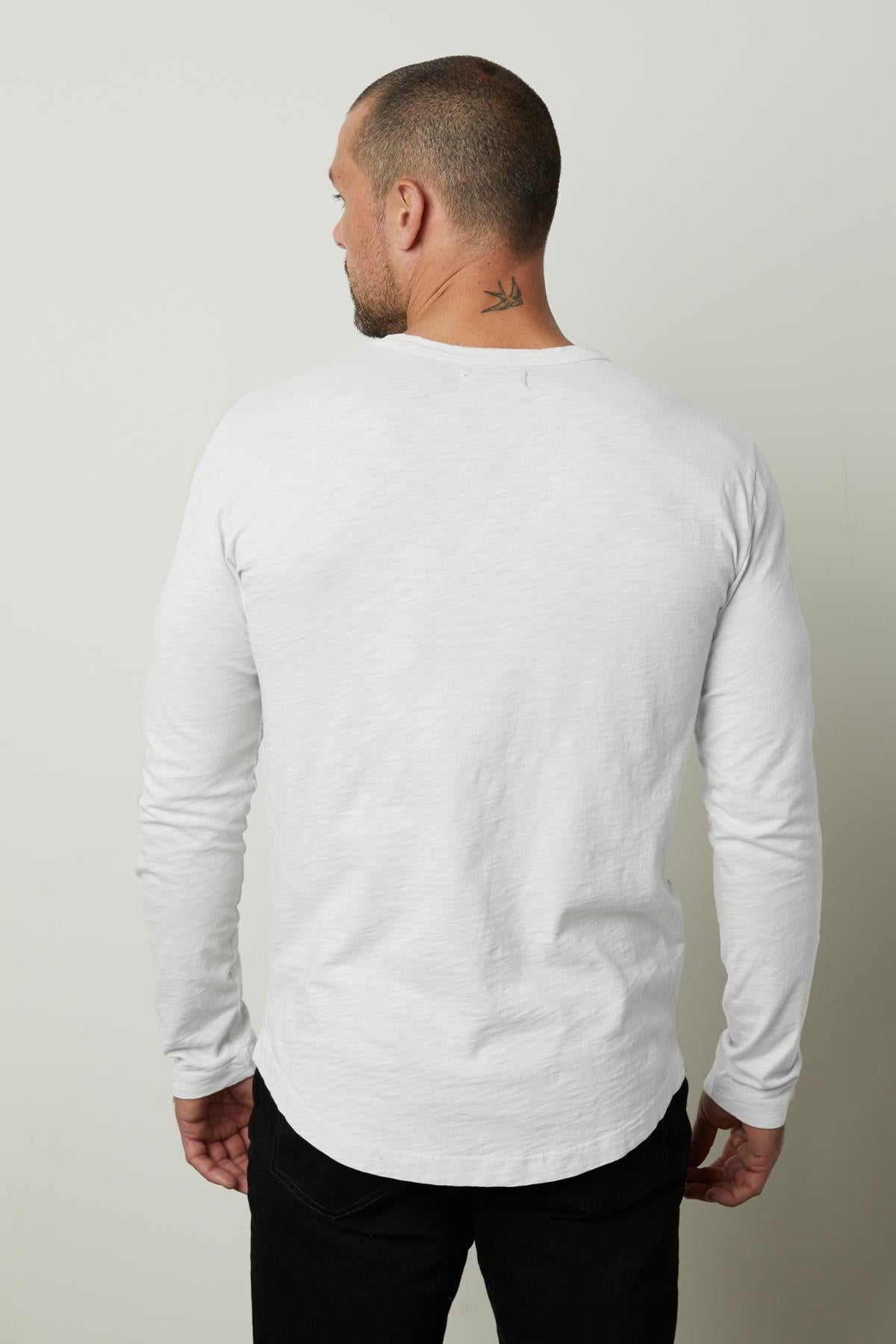   The back view of a man wearing a white Velvet by Graham & Spencer KAI CREW NECK TEE, showcasing its flawless fit. 