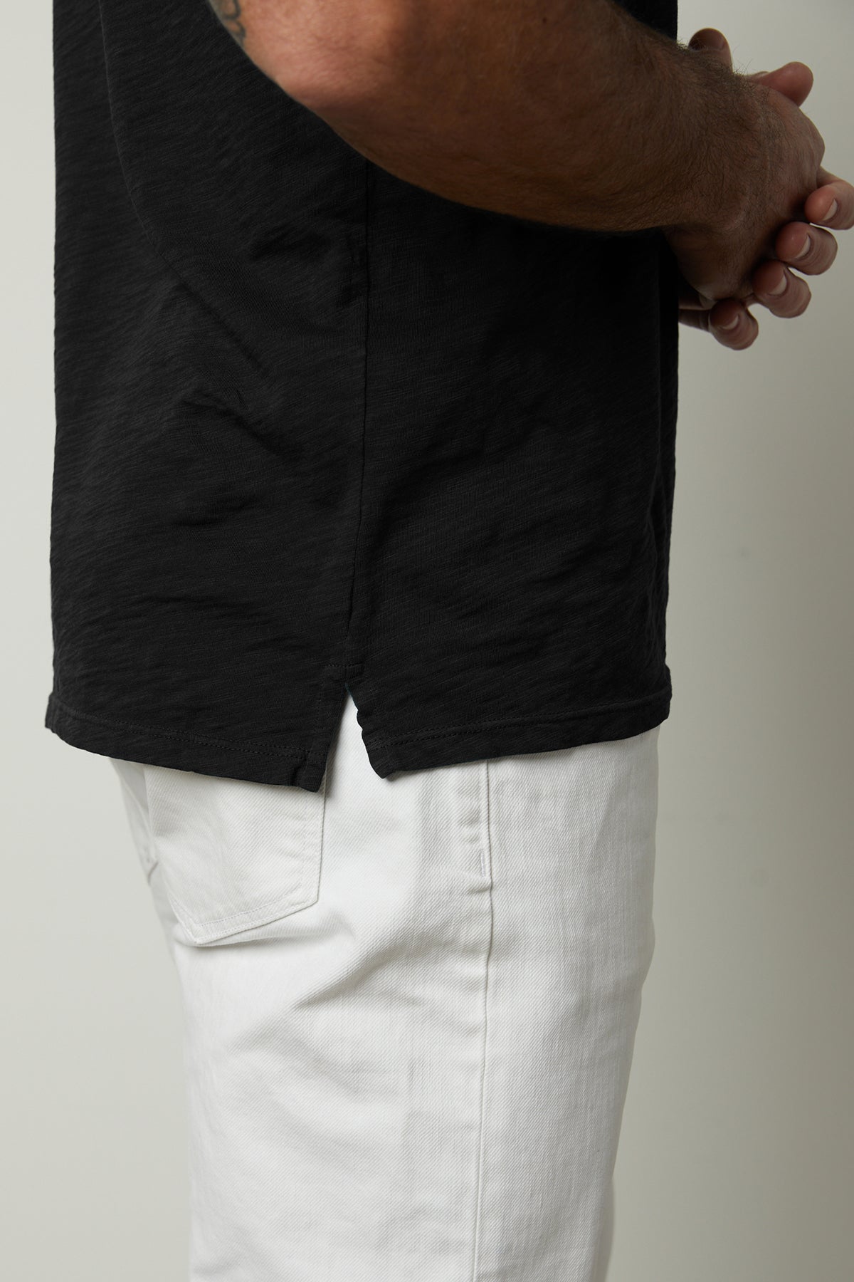   Niko Polo in black collared short sleeve shirt with white pants side split hem view 