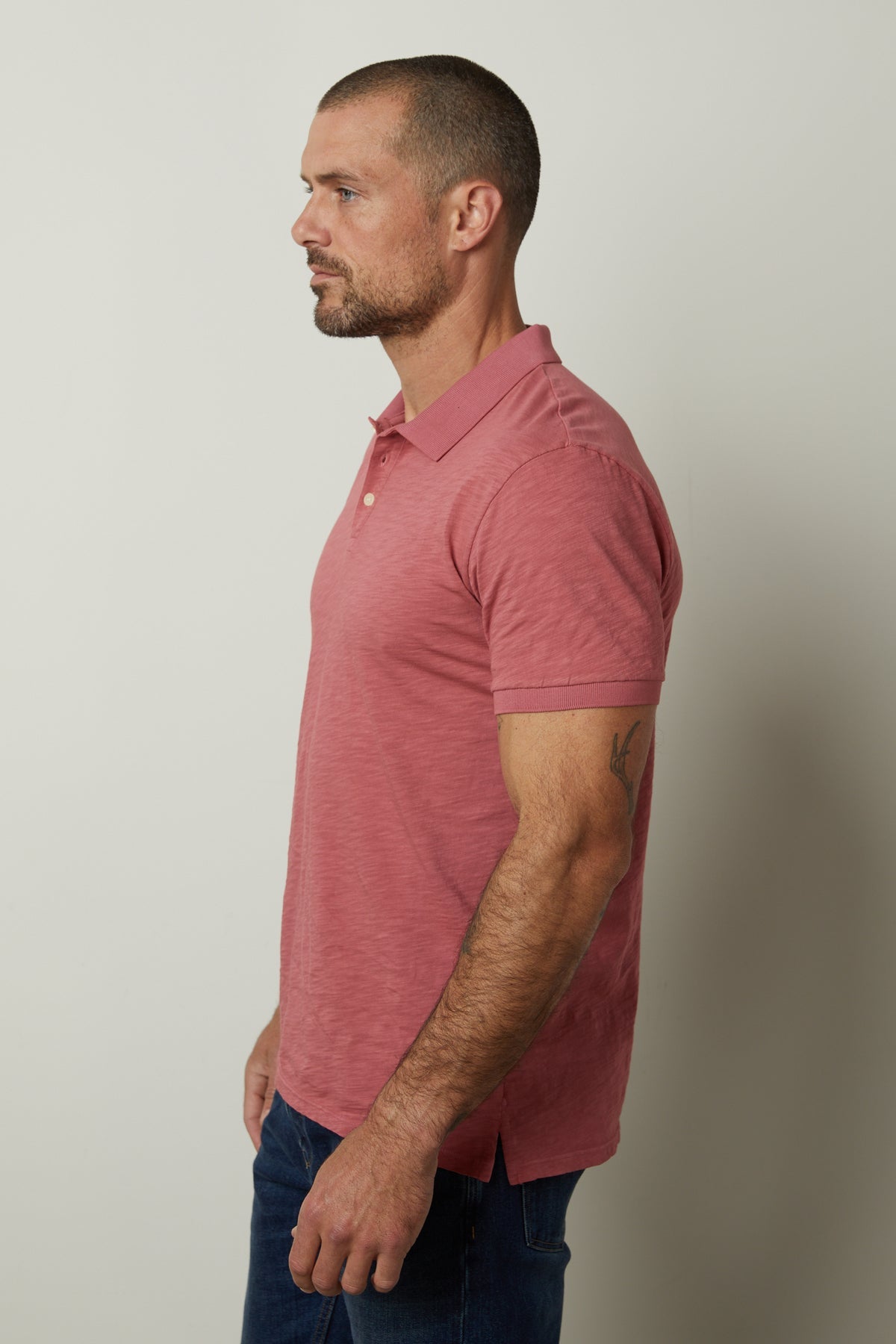   A man wearing a NIKO POLO shirt from Velvet by Graham & Spencer and jeans. 