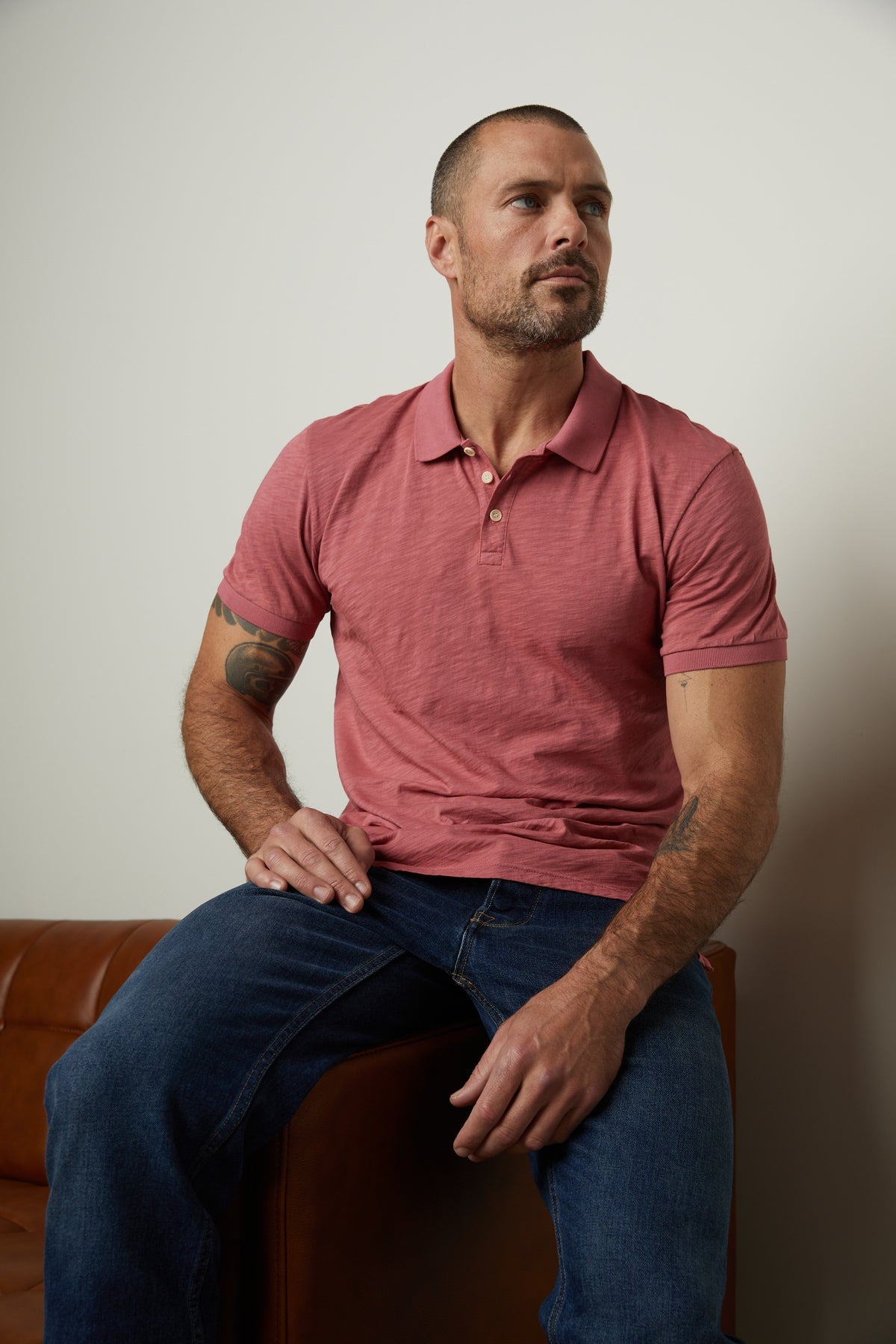   A man sitting on a couch wearing a NIKO POLO shirt by Velvet by Graham & Spencer. 