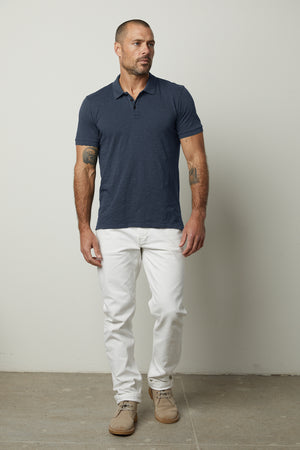 A man wearing a NIKO POLO shirt by Velvet by Graham & Spencer and white pants.