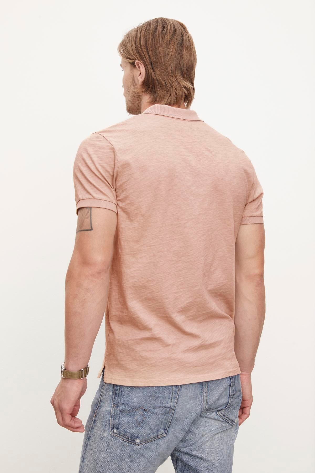Man in a Velvet by Graham & Spencer NIKO POLO and blue jeans, viewed from behind, revealing a tattoo on his left arm.-36890746749121