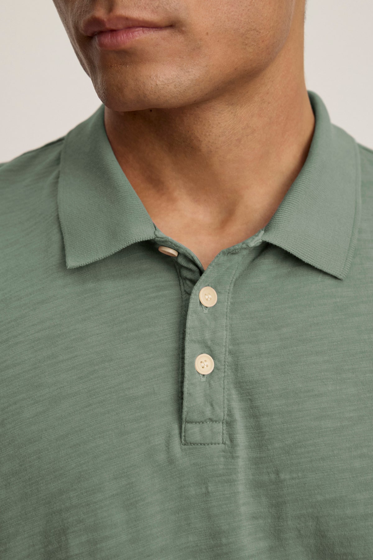   A person wearing the Velvet by Graham & Spencer NIKO POLO, a light green collared shirt with a 3-button placket, shown from the shoulders to just above the lips. 