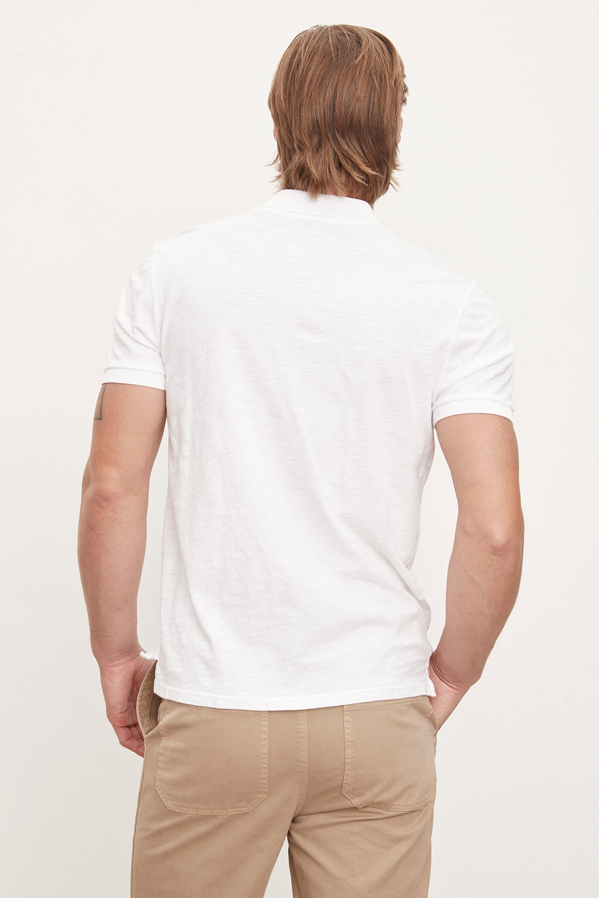 The back of a man wearing a Velvet by Graham & Spencer white cotton slub NIKO POLO t-shirt and khaki pants.-36009424879809