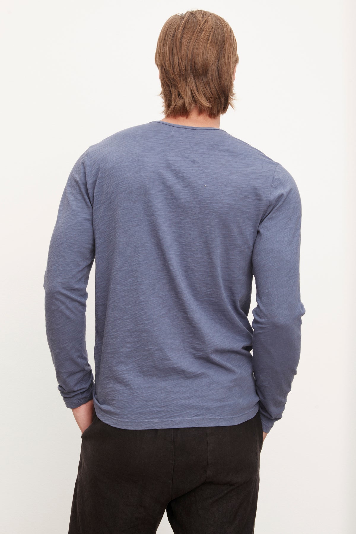 The back view of a man wearing a Velvet by Graham & Spencer SIMEON raw-edge cotton slub tee in blue, embodying California heritage.-36009054437569