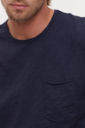 A close-up of a person wearing a Velvet by Graham & Spencer SIMEON RAW EDGE COTTON SLUB TEE with a chest pocket.