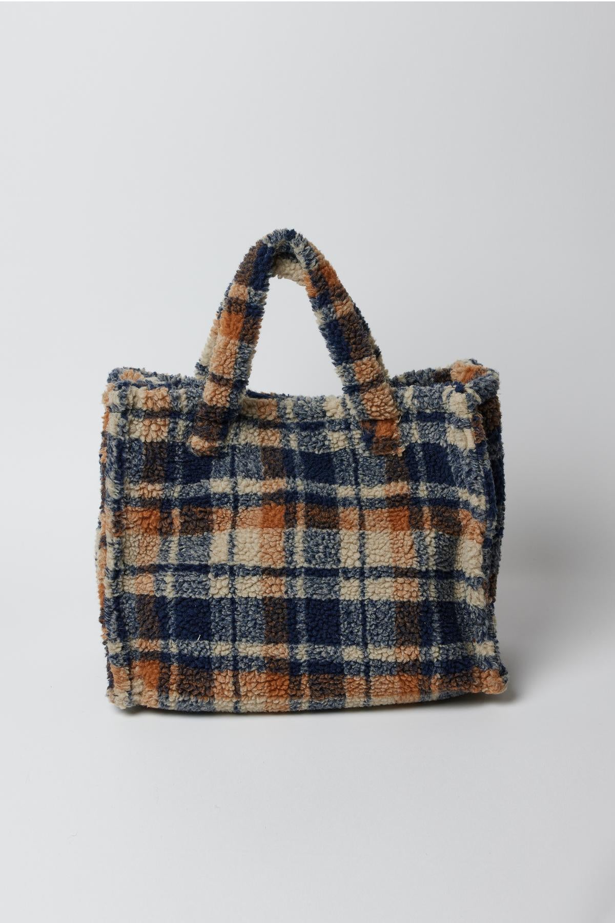   A blue and orange cold-weather SMALL TEDDY TOTE duffle bag by Velvet by Graham & Spencer on a white surface. 
