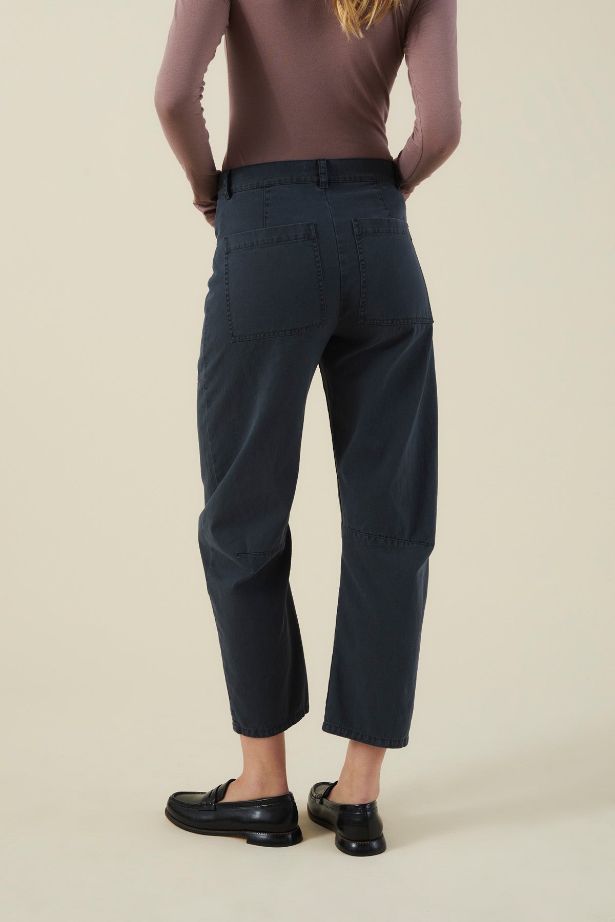 Back view of charcoal high-waisted barrel leg BRYLIE PANT with utilitarian patch pockets, paired with black loafers.