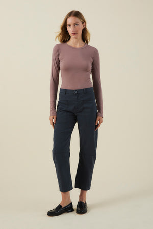 A model wears a long-sleeve mauve crewneck top, dark navy BRYLIE PANT barrel leg utility pants with front patch pockets, and black loafers.