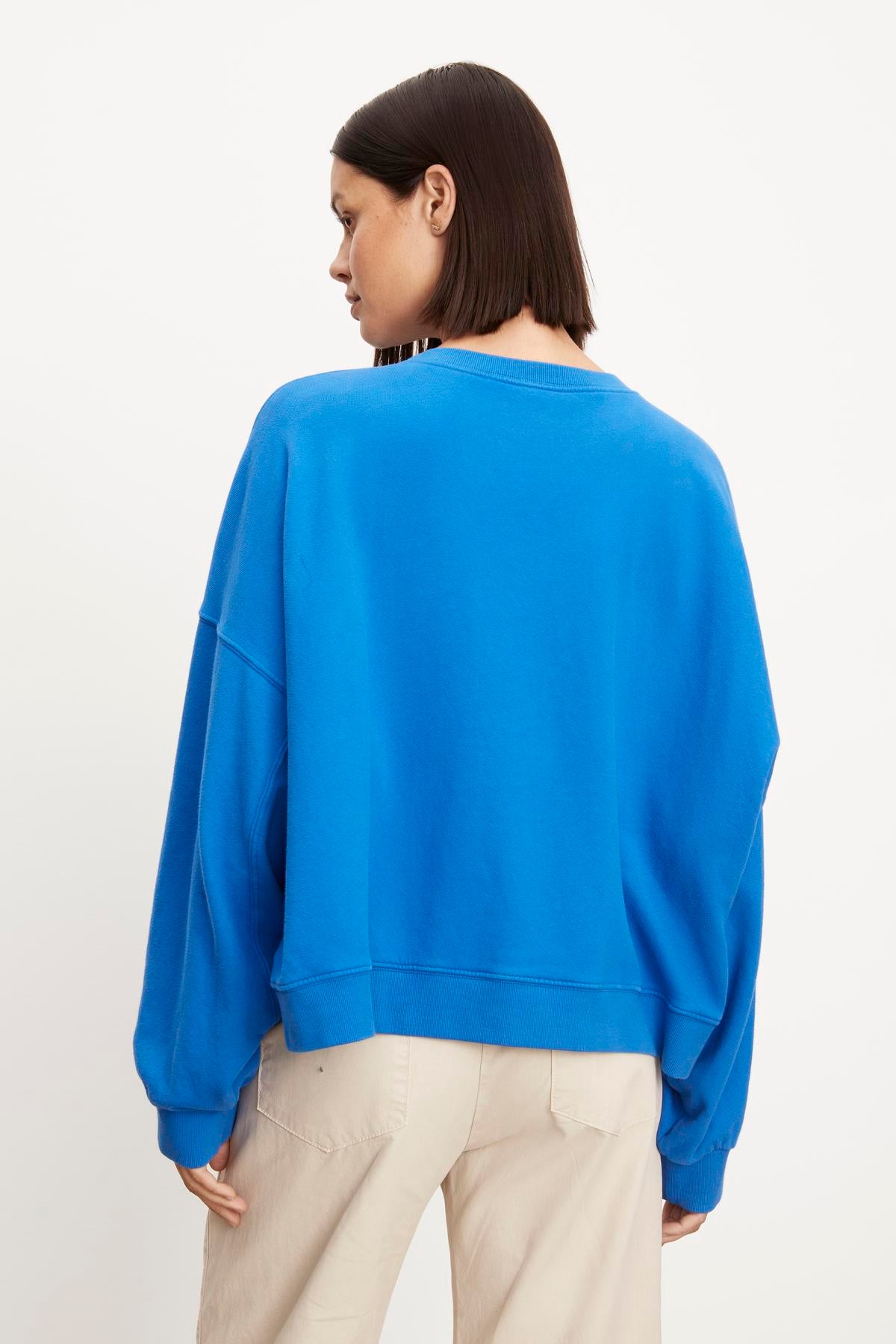 The back view of a woman wearing the Velvet by Graham & Spencer Margot Oversized Sweatshirt in soft fleece fabric.-35961316245697