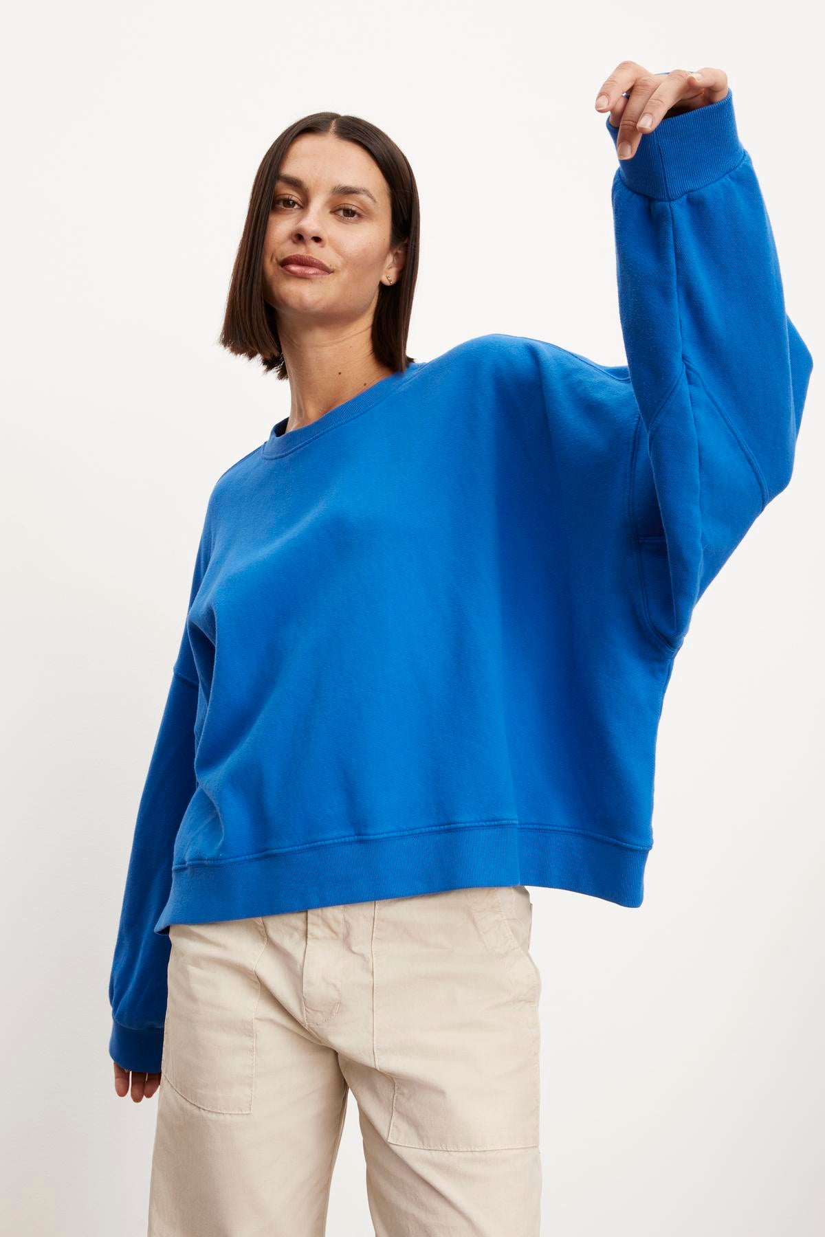 A model wearing the Velvet by Graham & Spencer Margot oversized sweatshirt made of soft fleece with relaxed and comfortable tan pants.-35961316049089