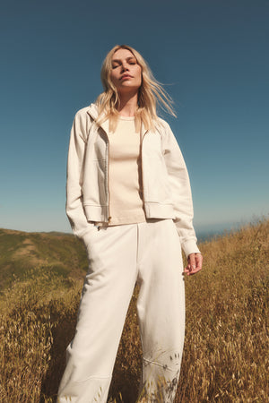 A woman standing in a white field wearing Velvet by Graham & Spencer's MATTY SOFT FLEECE SWEATPANT.