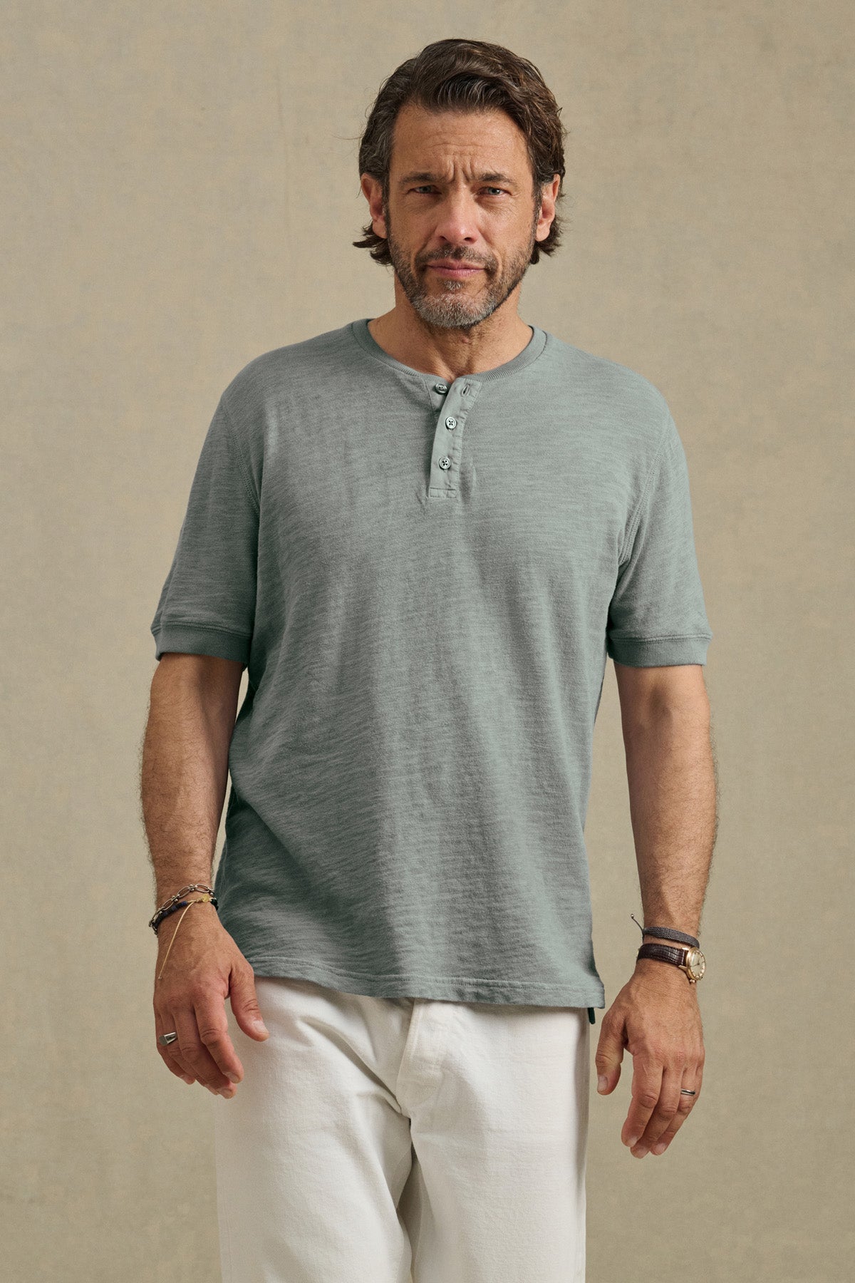 A man with short brown hair and a beard wears the Velvet by Graham & Spencer JENKINS HENLEY in light green and white pants, standing against a neutral background.-41145292751041