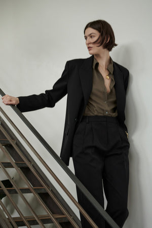 A person in a Velvet by Jenny Graham REDONDO BUTTON-UP SHIRT silhouette leaning on a staircase.