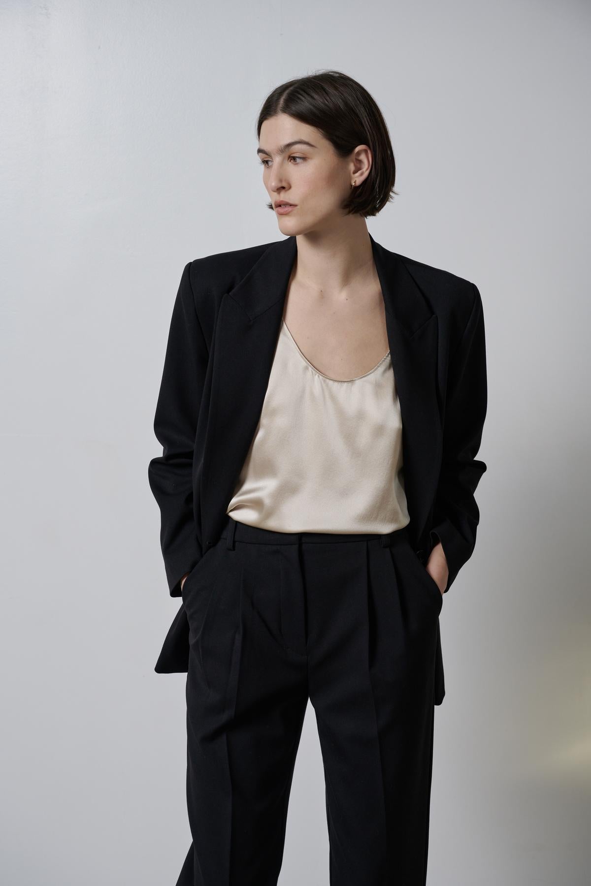 A woman wearing a black blazer and a white Velvet by Jenny Graham NOLITA TANK TOP blouse.-26829945405633
