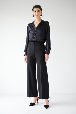 A woman wearing black wide leg PRINCE PANT with pleats and a blouse by Velvet by Jenny Graham.