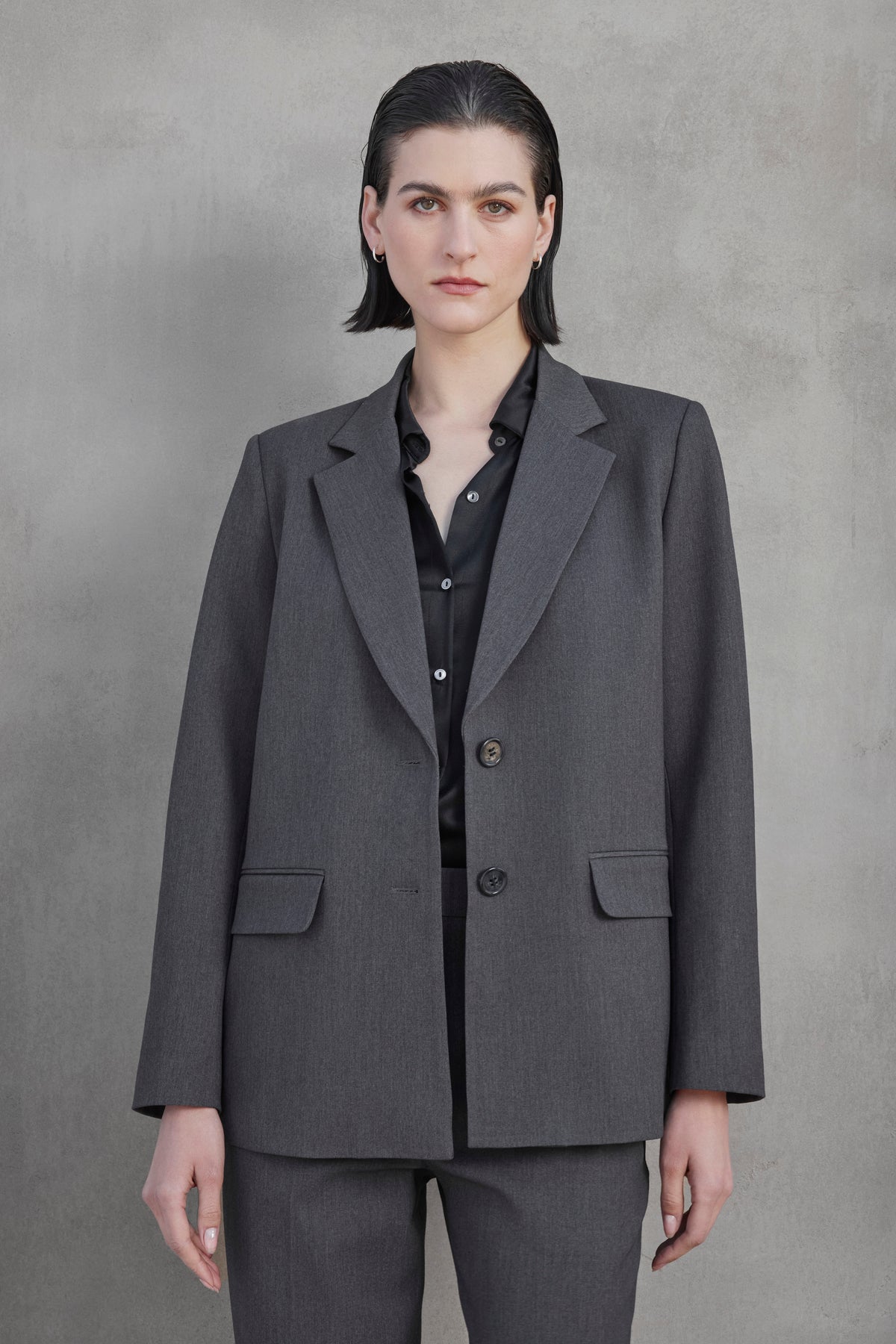 Individual with short hair clad in a REXFORD BLAZER by Velvet by Jenny Graham, paired with a black shirt, standing against a plain gray background.-37659969585345