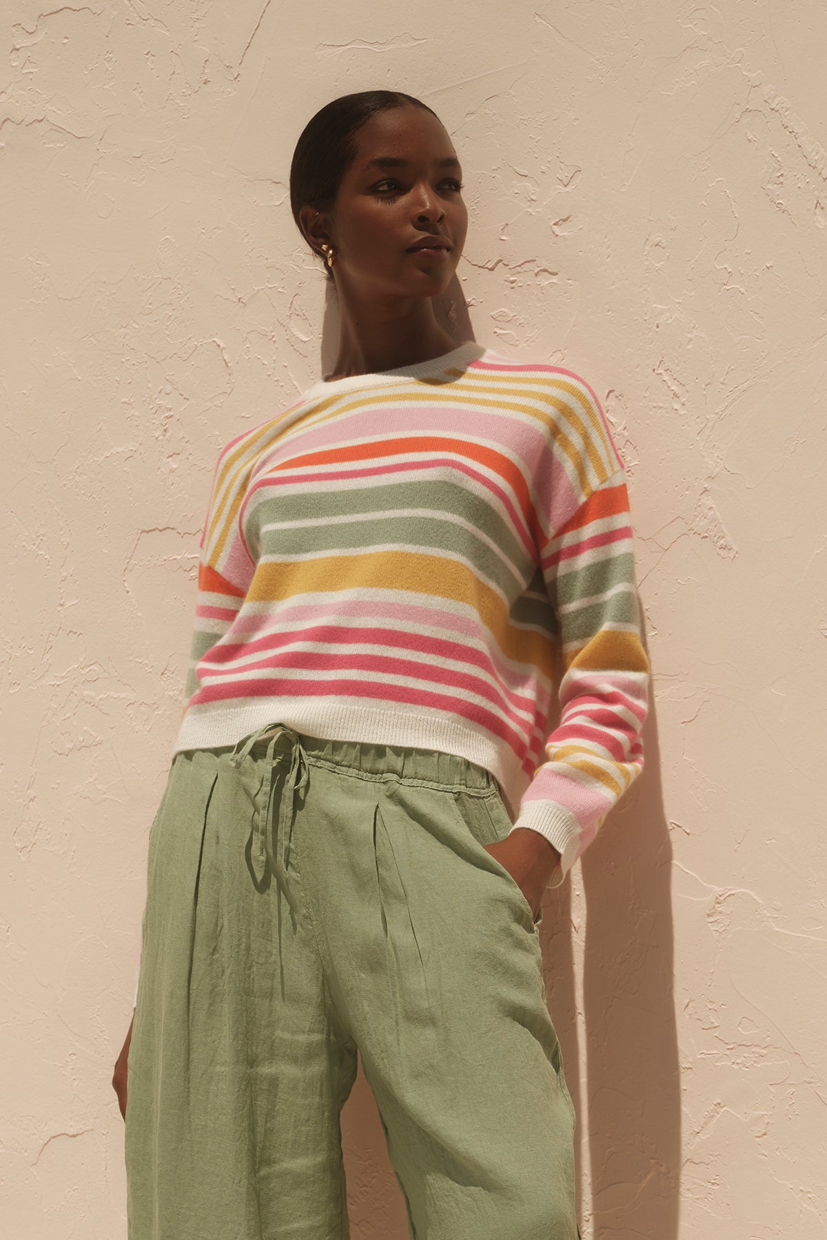   A woman wearing the Velvet by Graham & Spencer ANNY CASHMERE STRIPED CREW NECK SWEATER and lightweight green wide leg pants. 